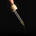 MYCOactor dropper pouring 1 ml of dual-extract with a black background